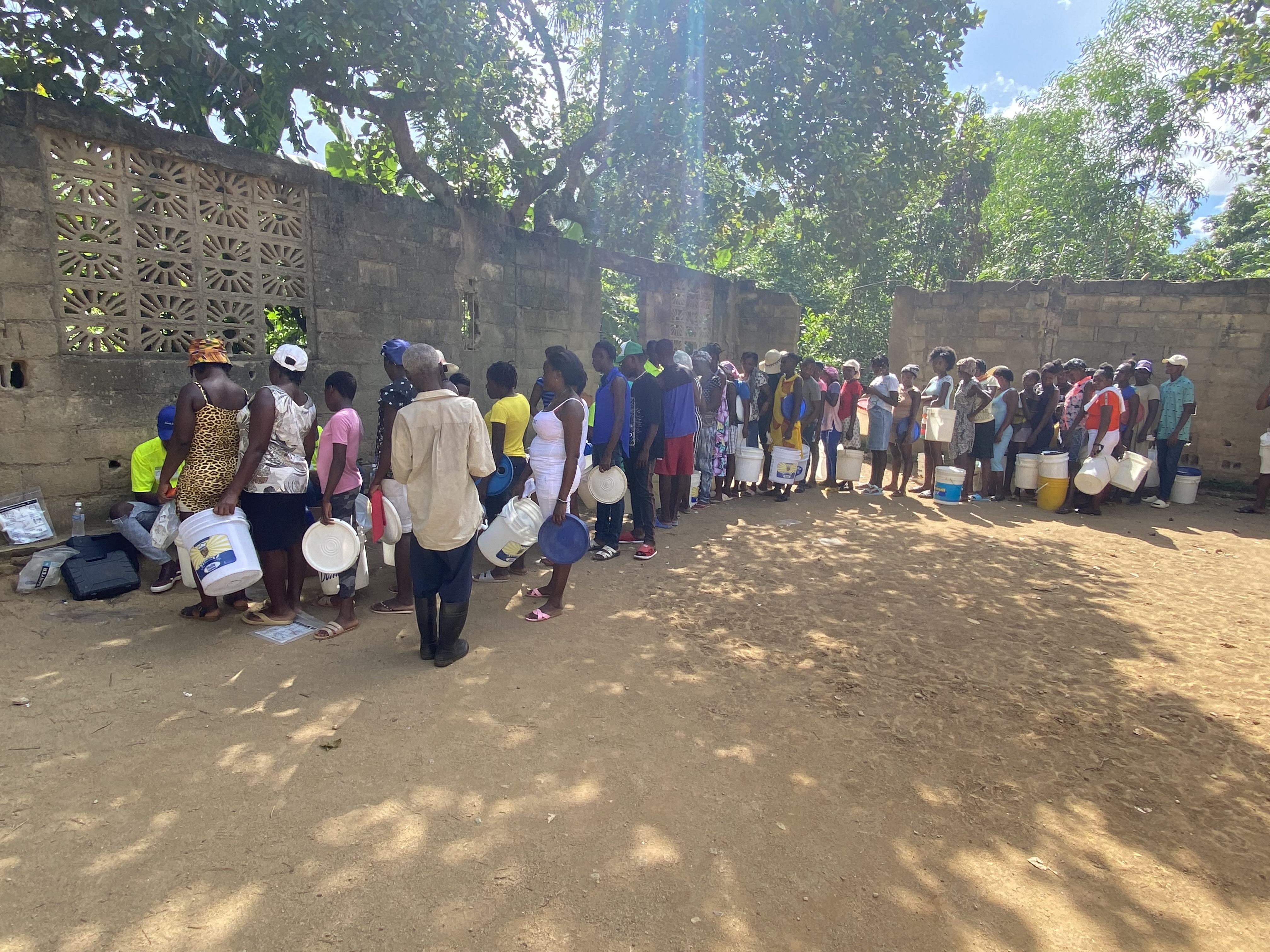 Villagers are lined up with their buckets to receive filters in them