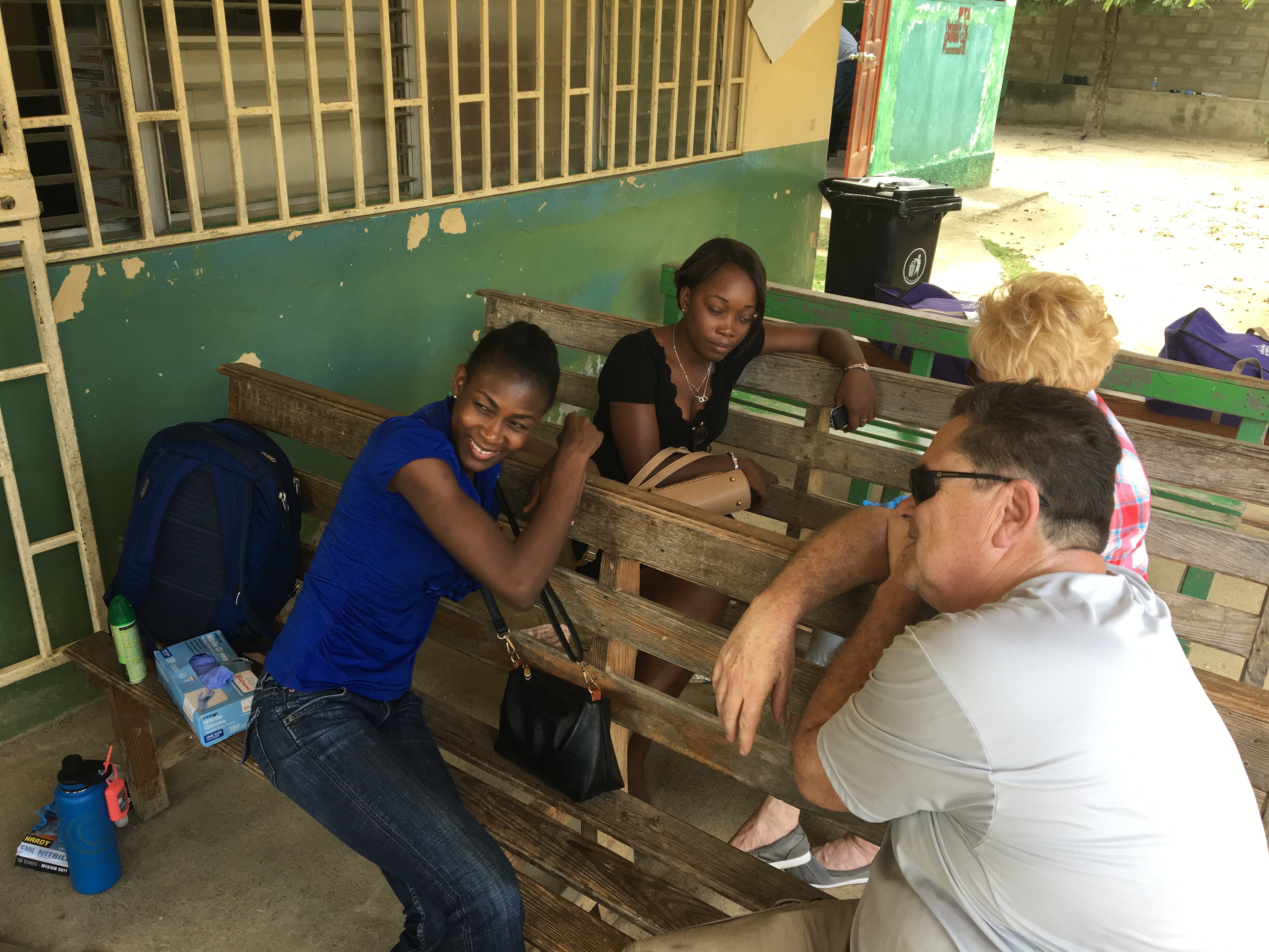 Marie-Claire (in blue, studied in the US and returned to be the mission team liaison for the school) and an assistant joined the team for a water distribution. Roger and Shareen share a moment with them as we prepare to set up in front of this USAID field office.